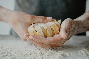 Person formt Nudeln auf einer bemehlten Fläche